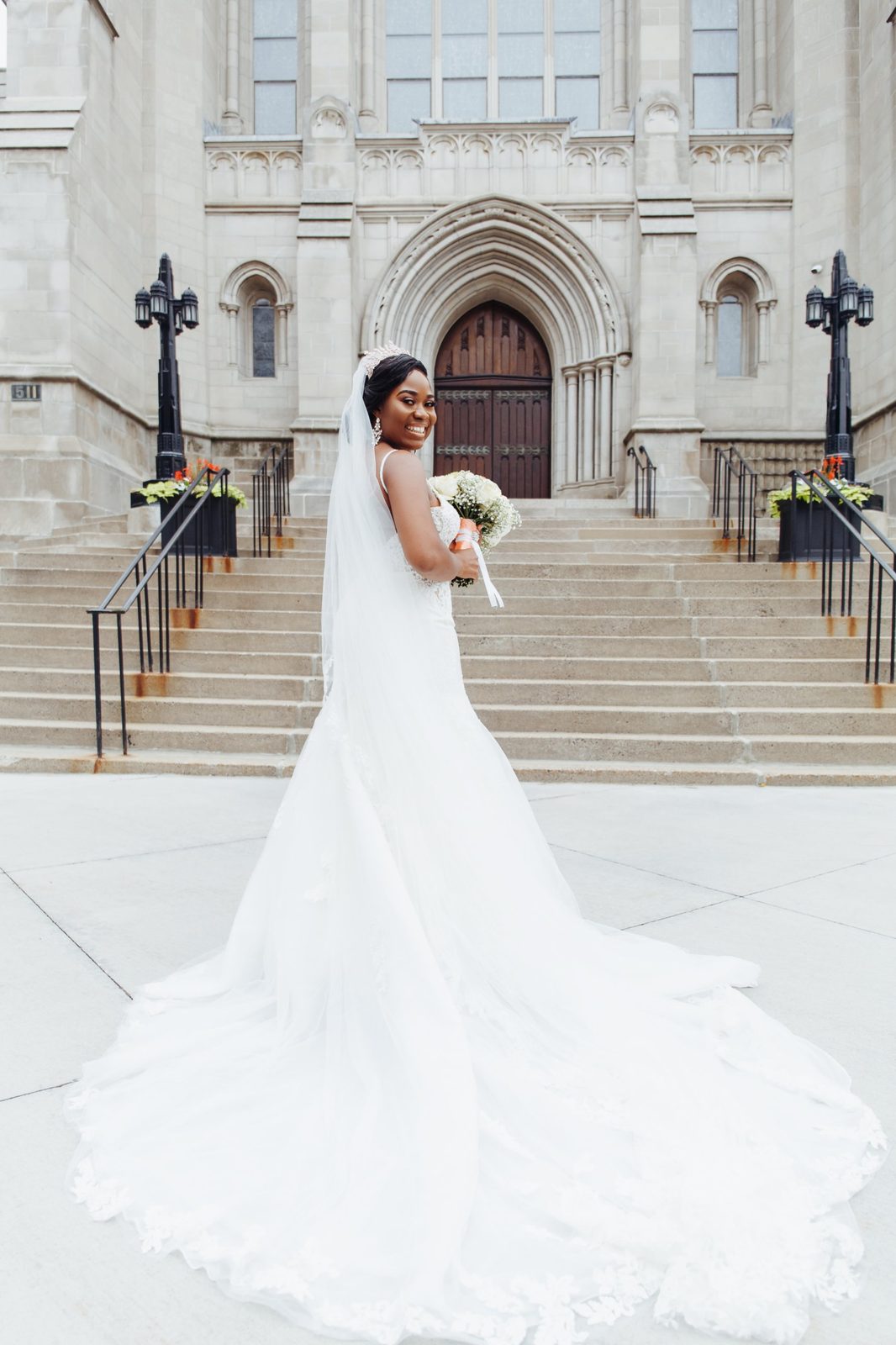 Bride on cathedral steps, her train fanned behind her